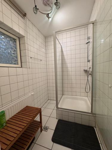a white tiled bathroom with a shower and a tub at schöne Monteurwohnung nach am Ulm in Dornstadt