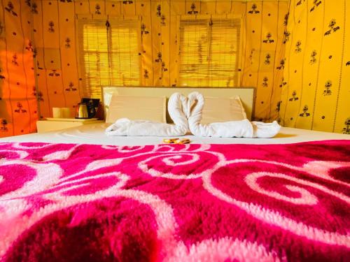 a bedroom with a pink bed with two towels at Uphill Adventures and Meditation I Dharamshala in Dharamshala