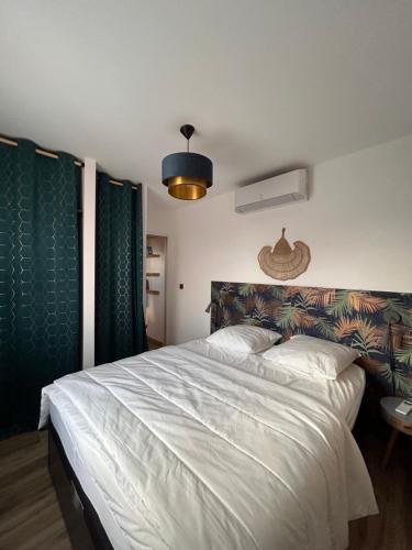 - une chambre avec un grand lit blanc et des rideaux verts dans l'établissement Au bonheur du Fez, à Orgnac-lʼAven