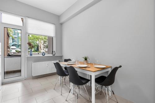 a dining room with a wooden table and black chairs at Domloge Lofts & Apartments in Cologne
