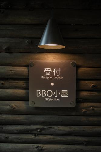 a sign hanging on a wooden wall with a lamp at コトトキス in Shizuoka