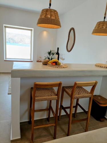 a kitchen with a counter with two chairs and a table at Vive Mare Milos in Pachaina