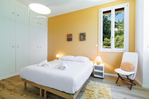 une chambre avec un lit, une chaise et une fenêtre dans l'établissement VILLA MONTE CRISTO - Villa conviviale a Nice - Superbe vue, piscine et jeux en plein air, à Nice