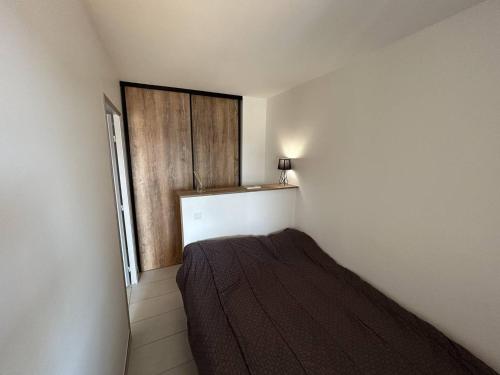 Cette petite chambre comprend un lit et une porte en bois. dans l'établissement Appartement moderne 4-6 pers, proche plage - Argelès-sur-Mer - FR-1-388-97, à Argelès-sur-Mer