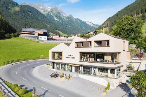 a building on a road with mountains in the background at Apart Sport-Stock in Finkenberg