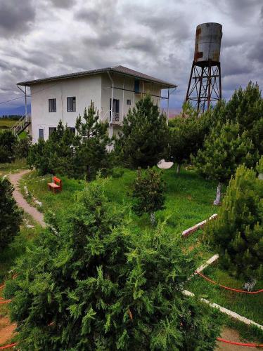 a house and a water tower in a field with trees at Arnabat Guest house in Bosteri