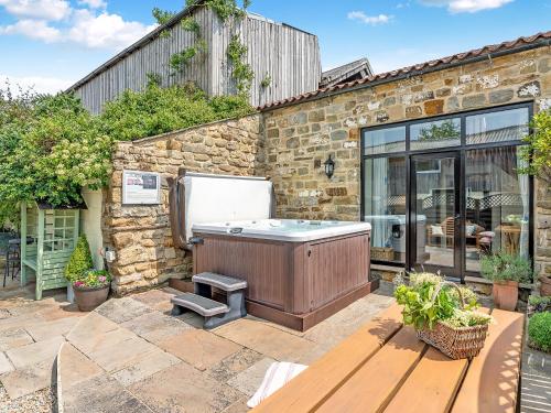 a hot tub in the backyard of a stone house at The Dairy in Beck Hole