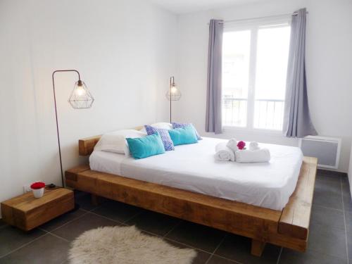 - une chambre dotée d'un grand lit avec des draps blancs et des oreillers bleus dans l'établissement Appartement 6 voyageurs, terrasse, piscine et parking privé, à Fréjus