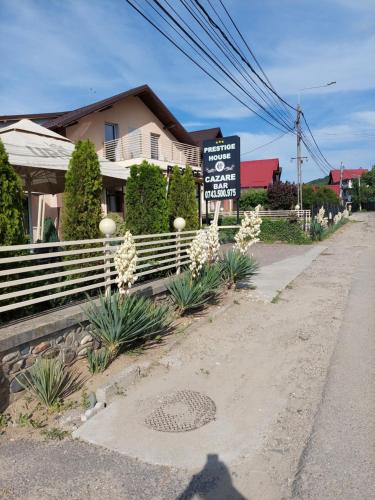 a sign on the side of a street with a house at Pensiunea Prestige House in Curtea de Argeş
