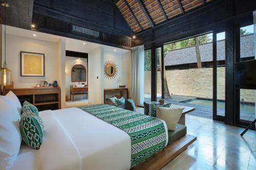 una camera da letto con un grande letto bianco e una scrivania di The Sebali Penida Beach Resort a Nusa Penida