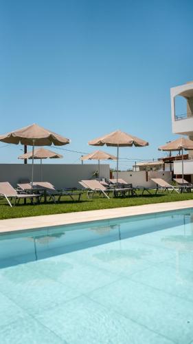 a swimming pool with chairs and umbrellas at Pinelopi Hotel in Platanes