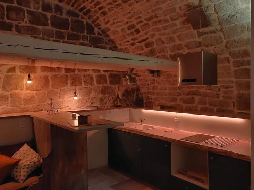 a kitchen with a counter and a brick wall at La cave des amoureux in Vogüé