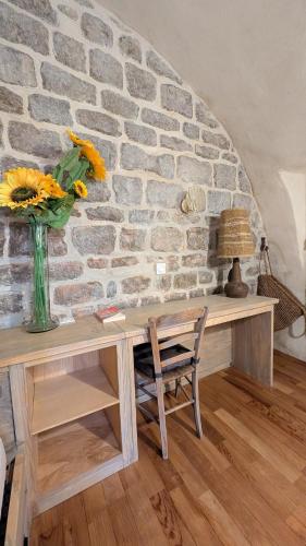 une table avec un vase de fleurs sur un mur de briques dans l'établissement La cave des amoureux, à Vogüé