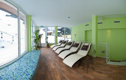 a row of white chairs in a room with green walls at Naturhotel Hüttenwirt im Grossarltal in Hüttschlag