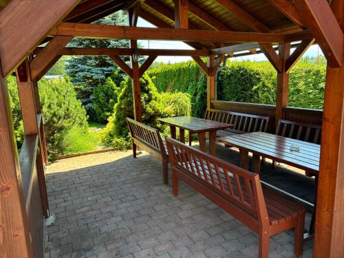 a wooden gazebo with benches and tables on a patio at Ubytovanie u Rebeky in Liptovská Teplá