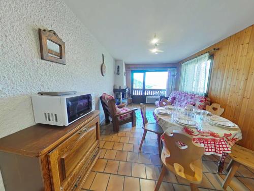 - un salon avec une table et un four micro-ondes dans l'établissement Appt cosy 3 pièces avec cheminée, proche télécabine - FR-1-241-42, au Grand-Bornand