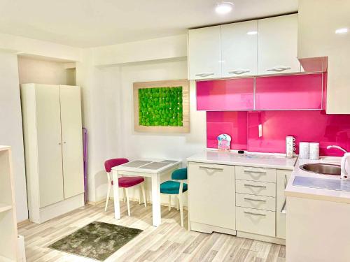 a kitchen with pink cabinets and a table and chairs at City Center Sweet Apartment in Niš