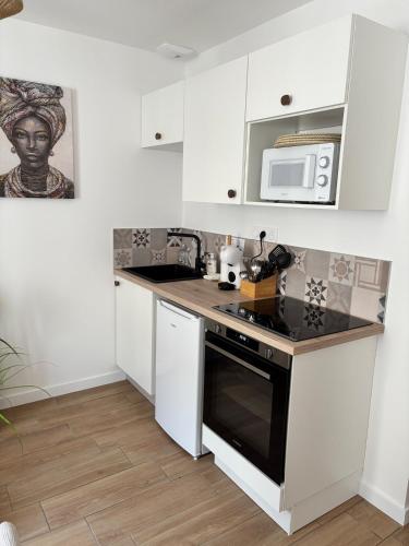 La cuisine est équipée de placards blancs et d'un four avec plaques de cuisson noires. dans l'établissement La case sénégalaise, à Cholet