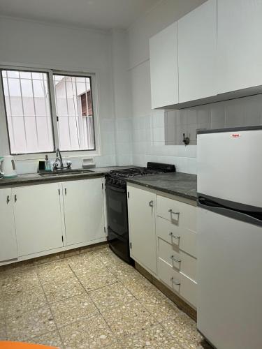 Una cocina con gabinetes blancos y un refrigerador blanco. en Departamento 54, en La Plata