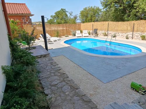 a small swimming pool in a yard with a fence at Apartment Laura - with PRIVATE swimming pool in Šibenik
