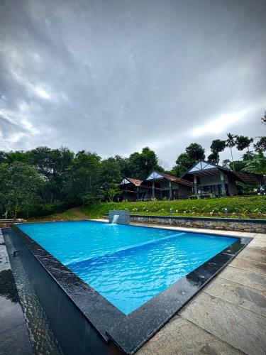 a large blue swimming pool in front of a house at Meghamalhar in Mānantoddy