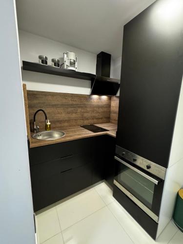 a small kitchen with black cabinets and a sink at Studio apartman Boogie in Krapinske Toplice