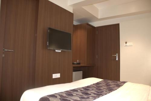 1 dormitorio con 1 cama y TV de pantalla plana en Hotel Sai Sanidhya, en Thane