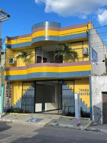 a yellow building with a fence in front of it at Pousada Maria Bonita - Centro, 10min da Praia de Camapum, Macau RN in Macau