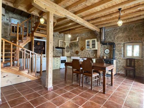 una sala da pranzo con tavolo in legno e scala di Traditional Stonehouse at Prementinos Village Lefkada a Lazaráta