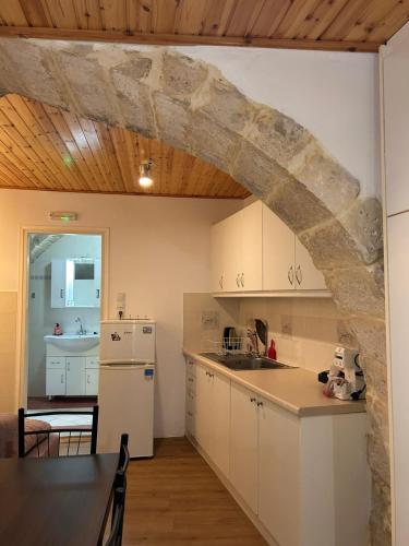 a kitchen with white cabinets and a stone wall at Rethymno traditional Studio in Rethymno Town