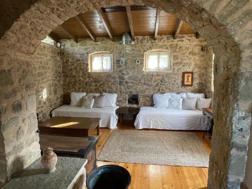 una camera da letto con due letti e un muro di pietra di Traditional Stonehouse at Prementinos Village Lefkada a Lazaráta