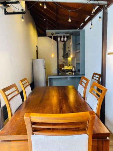 a large wooden table with chairs and a kitchen at Villa Navodi in Negombo