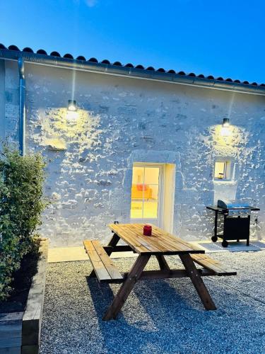 une table de pique-nique en bois devant un bâtiment dans l'établissement Gîte du dousset, à Esclottes