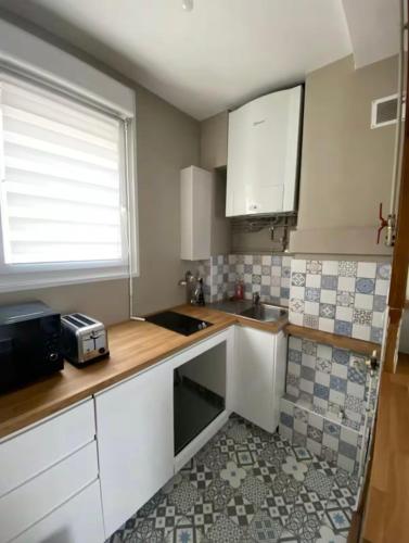 une petite cuisine avec des armoires blanches et un évier dans l'établissement Le Cosy, à Dijon