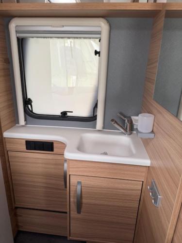 un bagno con lavandino e finestra di Premium Wohnwagen Nr 12 im Heide Resort Brüggen a Brüggen