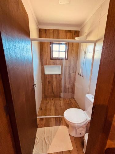 a small bathroom with a toilet and a window at Chalés Canto da Serra in São Bento do Sapucaí