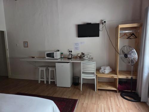a room with a desk and a table with a microwave at Koo Karoo Guest Lodge and Self Catering in Montagu