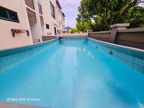 a swimming pool with blue water in front of a building at Cozy Villa - Private Pool, 5BR, KTV, BBQ, PS5 just 3 Mins to Batu Ferringhi Beach! in Batu Ferringhi