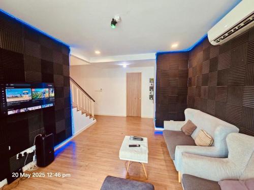 a living room with a couch and a tv at Cozy Villa - Private Pool, 5BR, KTV, BBQ, PS5 just 3 Mins to Batu Ferringhi Beach! in Batu Ferringhi