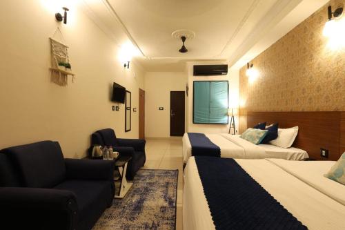 a hotel room with two beds and a couch at Hotel Amarah in Jaipur