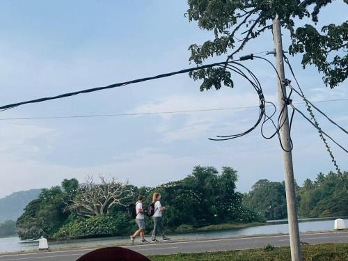 two people walking down a road next to a river at Tissa Yala Lake View Hotel in Tissamaharama