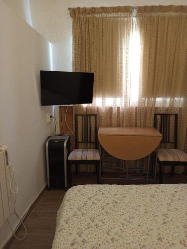 una camera da letto con un letto, due sedie e una televisione di La Casa del Patio ATQ ad Antequera