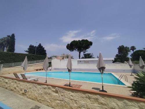 ein Pool mit Sonnenschirmen in einem Resort in der Unterkunft OasiMareBlu in Marina di Ragusa