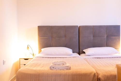a bed with a large headboard and two towels on it at Stone Palace Hotel Near Athen's Airport Free Shuttle From and to Athen's Airport in Spáta