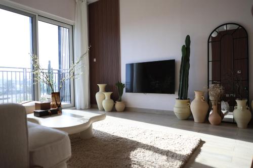 a living room with a tv and a lot of vases at Desert Home Abu Dhabi in Abu Dhabi