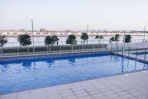 a swimming pool with blue water and a fence at Desert Home Abu Dhabi in Abu Dhabi