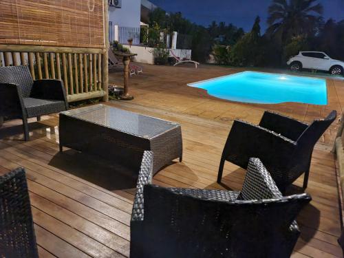 a wooden deck with chairs and a swimming pool at Lazy Tilapia in Baie du Tombeau
