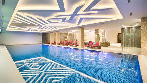 a pool in a hotel with red chairs at Time Out Lux apartmani in Zlatibor