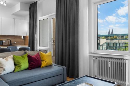 a living room with a couch and a large window at Domloge Lofts & Apartments in Cologne
