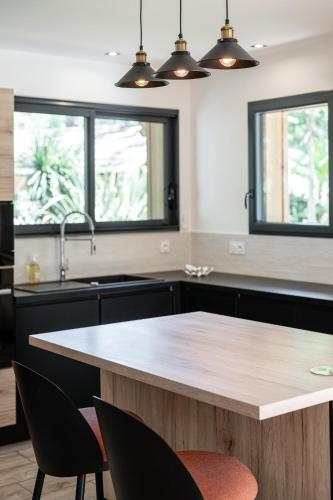 - une cuisine avec une table en bois et 2 fenêtres dans l'établissement Cabane 19, à Biscarrosse